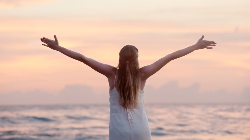 woman on beach with outstretched arms